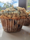 Wild blueberry muffin with a crumbly topping on a white surface