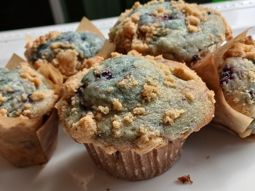 Blueberry muffins with crumb topping on a white surface