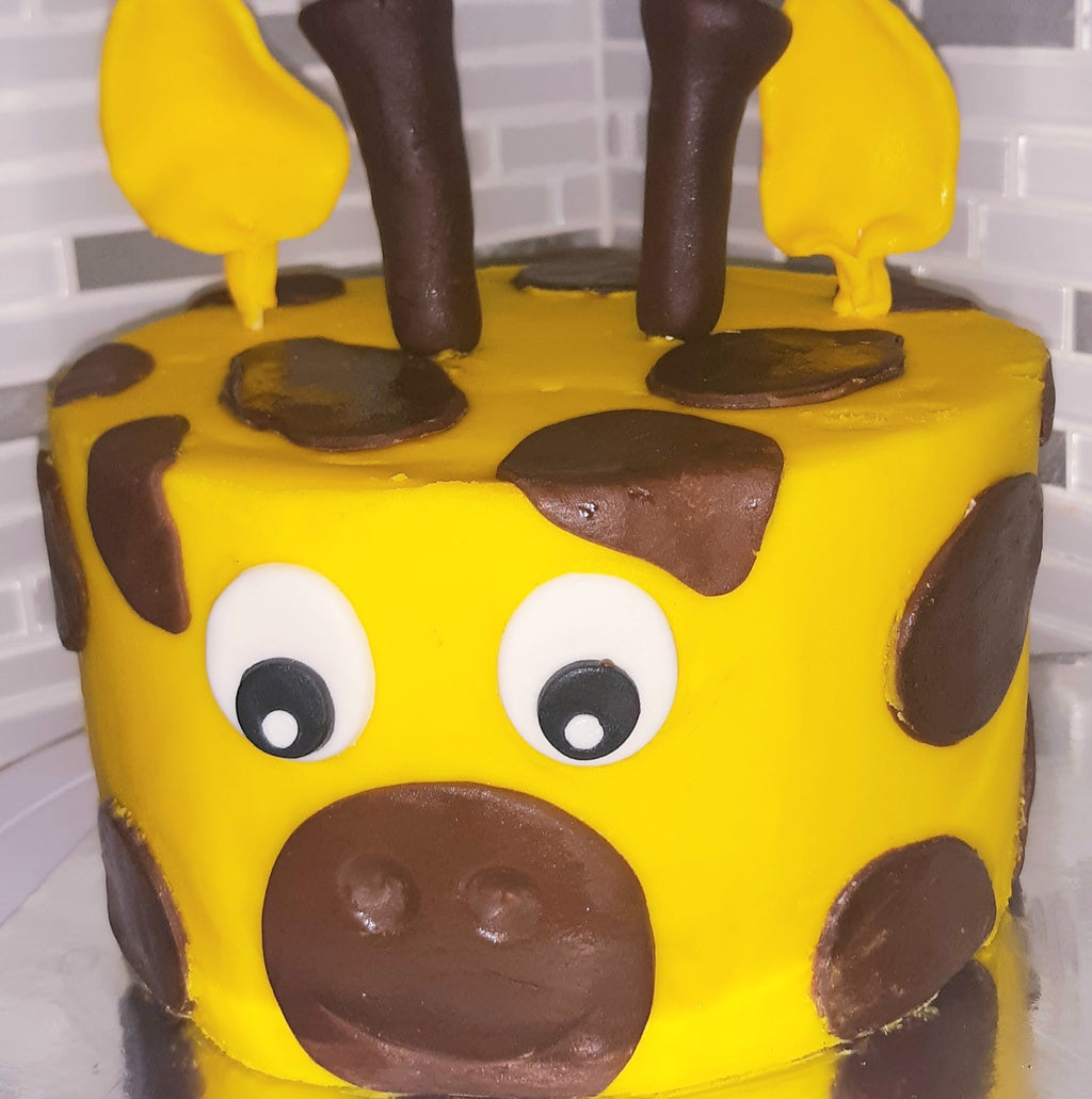 Yellow cake with brown spots and a face on a white surface, Giraffe 3D cake