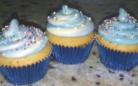 Vanilla cupcakes with blue and white swirled frosting on a speckled countertop
